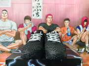 Front view of the sneakers showing the white laces, textured toe boxes and black outsoles.