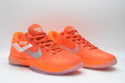 Front three-quarter view of bright orange Nike basketball sneakers with silver Swooshes, textured uppers, and Kobe-style tongue logos.