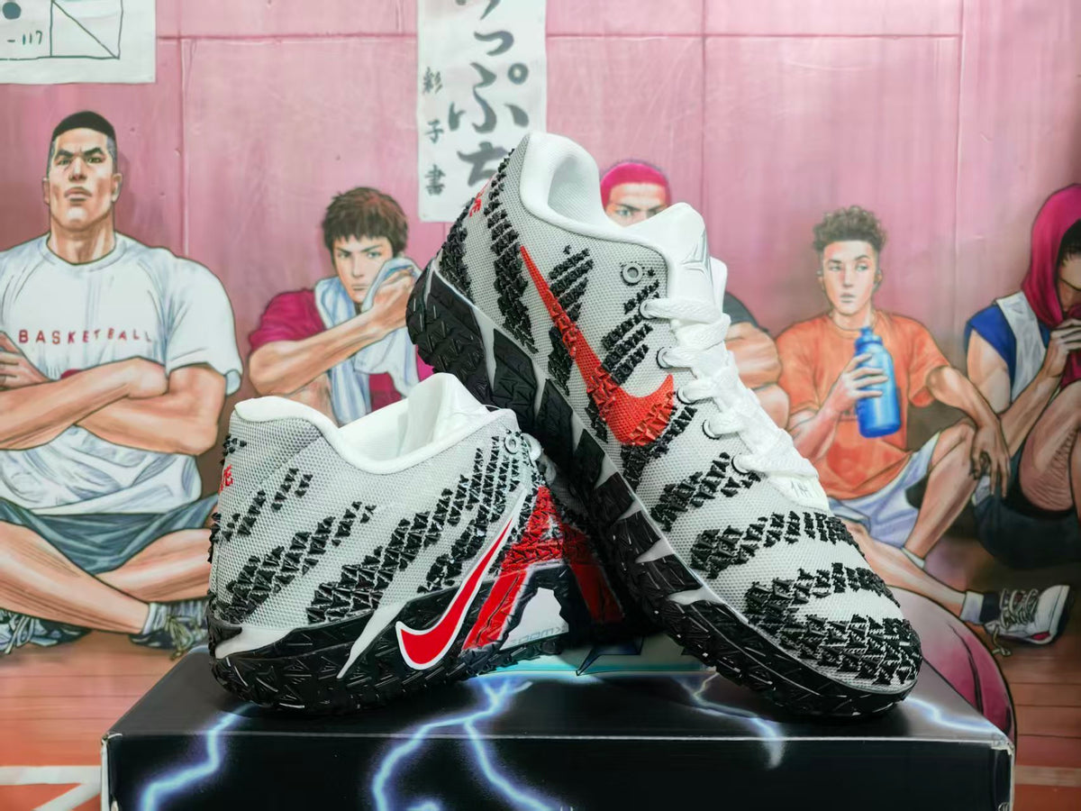 White Nike basketball shoes with black geometric patterning, red accents, and black textured outsoles.