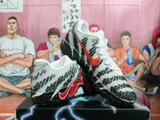 White Nike basketball shoes with black geometric patterning, red accents, and black textured outsoles.