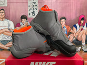 Angled view of the gray and orange high-top sneakers showing layered uppers, orange lining, black overlays, and textured soles.