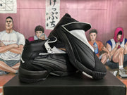 Angled view of paired black and white Jordan high-top sneakers showing the side construction, zipper detail, and rubber outsoles.