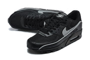 Angled view of black Nike Air Max 90 sneakers with silver Swoosh accents.