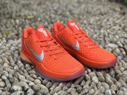 Front angled view of the pair with orange laces, textured uppers, and silver Swooshes.