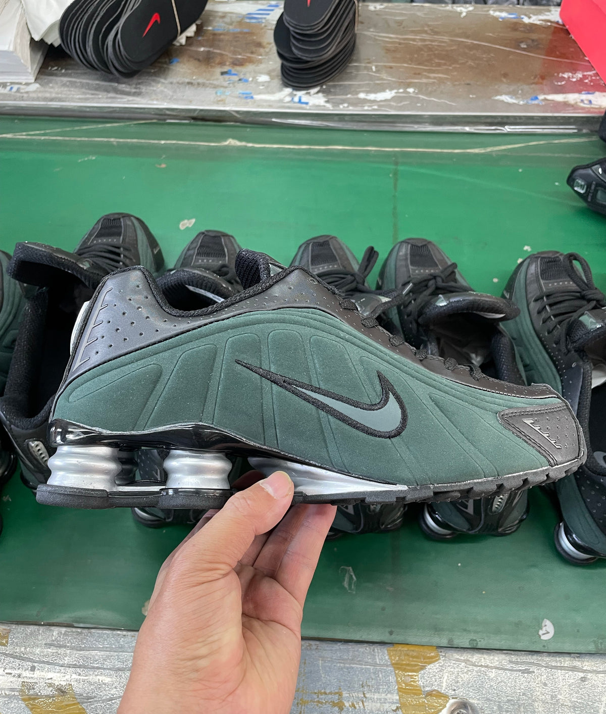 Dark green and black Nike Shox-style low-top sneaker with perforated panels and heel cushioning columns