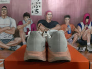 Rear view of white Nike sneakers with pink and orange heel and sole accents on an orange shoebox.