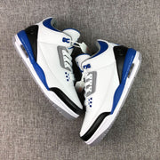 Top-down view of the pair highlighting the white uppers, blue collar lining, black heel panels, and blue midsoles.
