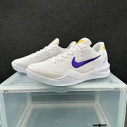 Pair of white basketball sneakers shown from a front-side angle, highlighting the purple Swoosh, white laces, and yellow heel accents.