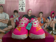 Front view of the pink basketball sneakers with white laces, orange accents, and textured white outsoles.