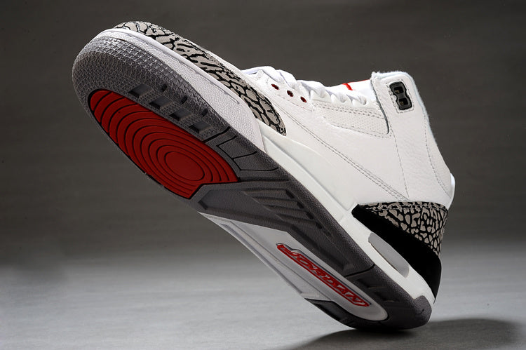 Underside view of a white and black Air Jordan 3 sneaker showing the gray and red outsole and elephant-print heel detail.