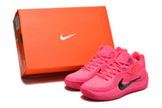 Pink Nike basketball sneakers displayed beside an orange Nike shoe box.