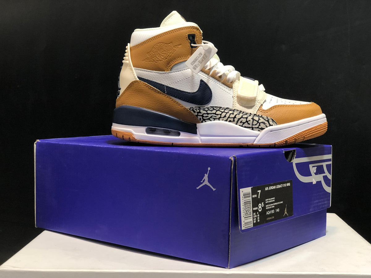 Jordan Legacy 312 sneaker shown on its box in white, tan, and navy with a visible box label.