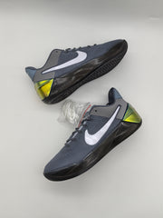 Cool grey Nike basketball sneakers shown from an angled outsole view, with dark tread and an additional pair of white laces.