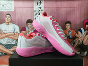 Angled view of the white and pink sneakers showing the mesh-like side panels, patterned lace area, and pink sole.