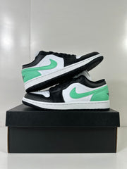 Pair of white, green, and black low-top sneakers arranged on a black shoebox.