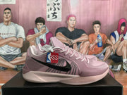 Pair of pink Nike basketball sneakers with black Swoosh detailing displayed on a black shoebox.