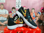 Angled view showing the black Nike sneakers, gold Swoosh, multicolor graphic upper, and white ribbed outsole.