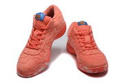 Pair of coral low-top sneakers shown from the front with blue tongue labels and silver outlined side swooshes.