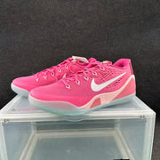 Pair of pink Nike basketball sneakers with white Swooshes displayed on a clear case.