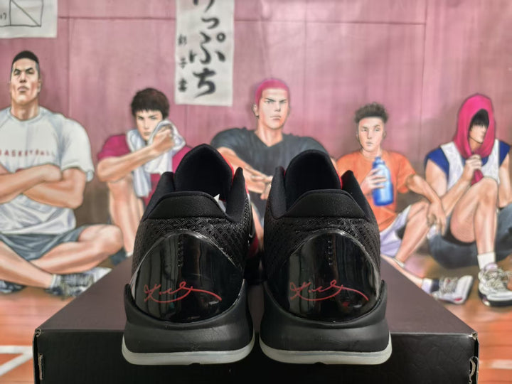 Rear view of black and pink Nike basketball sneakers showing glossy heel panels, red signature-style graphics, and translucent outsole edges.