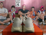 Rear view of a pair of light-colored Nike sneakers displayed on an orange shoebox.