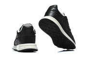 Rear and outsole views of black sneakers with white midsoles.