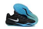 Black basketball shoe beside its blue-green patterned outsole