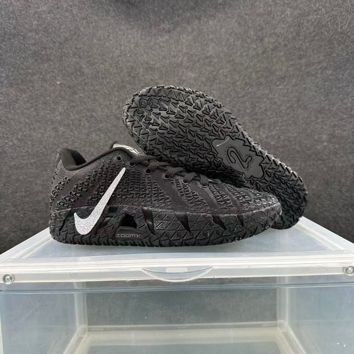 Black Nike basketball sneakers with silver Swoosh branding, shown from the side with one shoe lifted to reveal the patterned outsole.
