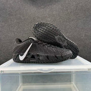 Black Nike basketball sneakers with silver Swoosh branding, shown from the side with one shoe lifted to reveal the patterned outsole.