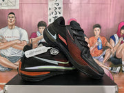 Angled view of the paired black and red basketball sneakers, showing the side panels, laces, heel accents, and outsoles.