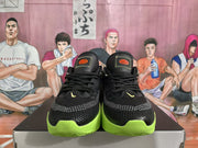 Front view of black Nike basketball sneakers with bright green soles, black laces, and orange tongue details.