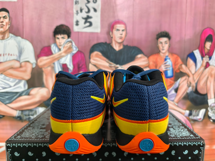 Rear view of navy Nike basketball sneakers with yellow heel panels and orange outsoles