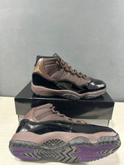 Air Jordan 11 Retro sneakers shown from the side and outsole, featuring a black and bronze color scheme with purple traction sections.