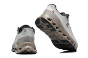 Rear and outsole views of the gray and taupe On Cloudmonster 3 sneakers