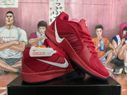 Pair of red Nike basketball sneakers shown from the side on a black box, with light-colored Swoosh logos and a basketball-themed background.