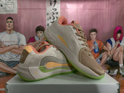 Angled view of the pair displaying the layered side construction, tonal laces, coral collar lining, and green outsole accents.