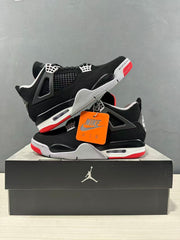 Black and red Jordan Air Jordan 4 sneakers displayed on a black shoebox with an orange hangtag.