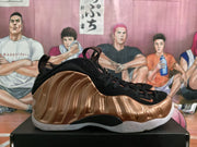 Side profile showing the sculpted bronze upper, black midfoot section, pull tabs, and white outsole.