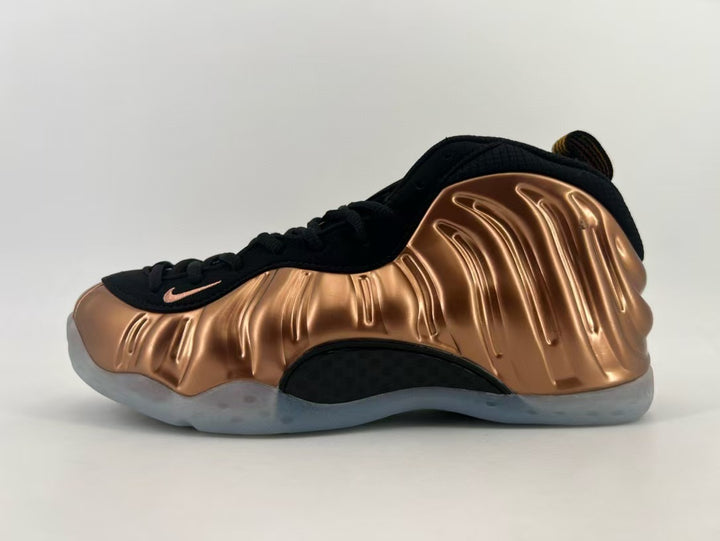 Side view of a copper-toned and black Nike Foamposite-style sneaker with sculpted panels and a translucent-looking outsole.