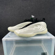 Three-quarter view of the silver and black sneaker pair displayed on a clear stand.