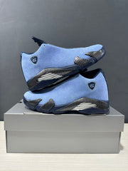 Pair of blue and navy Jordan Air Jordan 14 sneakers displayed in side profile on a shoe box.