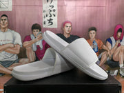 White Nike slides arranged at an angle to show the strap texture, footbed, and sole profile.