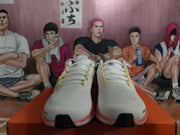 Front view of the pair showing the white perforated-looking uppers, yellow lace details, and black toe accents.