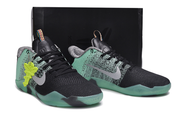 Mint green and black Kobe 11 sneakers displayed against a black background.