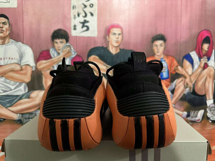 Rear view of black and orange basketball sneakers with black heel details.