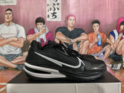 Side profile of a black Nike basketball sneaker with a large white Swoosh, textured upper, and layered black and white sole.