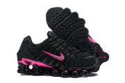 Pair of black and pink Nike Shox TL sneakers with one shoe showing the outsole
