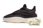 Side view of a black low-top lace-up sneaker with layered panels, cream outsole, and coiled laces.
