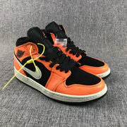 Angled view of the orange and black sneaker pair showing black laces and padded collars.