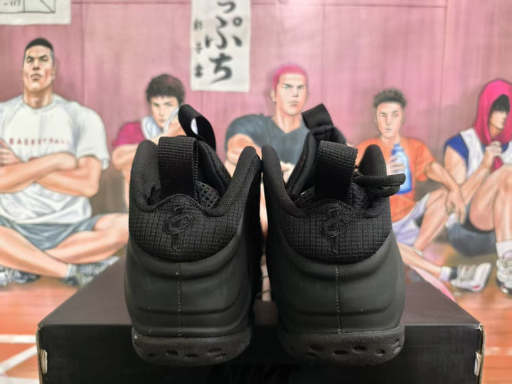 Rear view of a pair of all-black high-top basketball sneakers with heel pull loops.